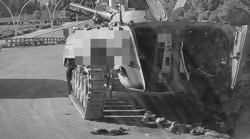 A wrecked armoured vehicle at a road junction.